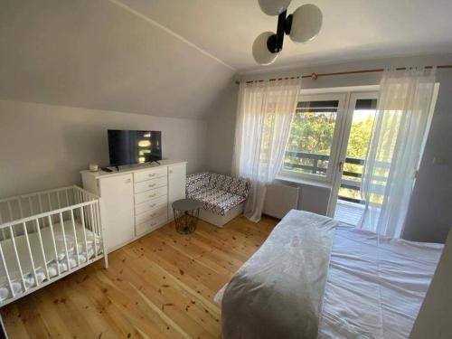 um quarto com um berço, uma cama e uma televisão em Dom Pod Sosnami em Mielno