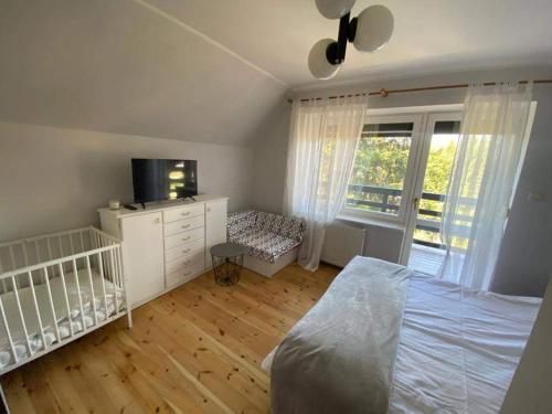 a bedroom with a crib and a bed and a tv at Dom Pod Sosnami in Mielno