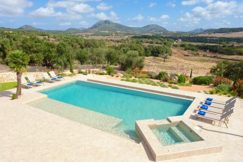 a swimming pool with chairs and mountains in the background at Sa Murtera in Manacor