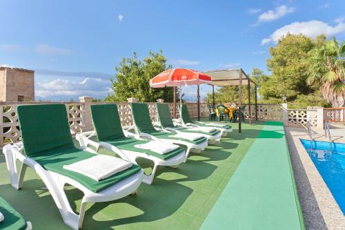 a row of chaise lounge chairs next to a swimming pool at Cas Fideuer in La Aranjasa