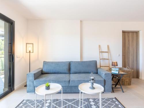 a living room with a blue couch and two tables at Apartment St Joseph-1 by Interhome in Porto-Vecchio