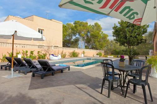a table with chairs and an umbrella next to a pool at Villa Angela in Urbanicacion ses palmeres