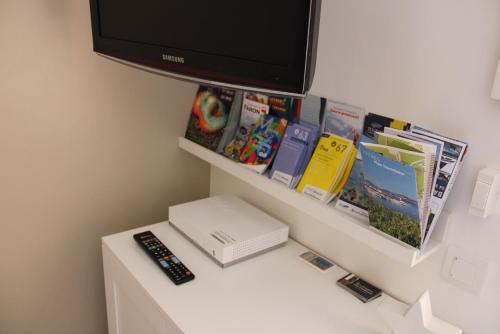 a tv sitting on top of a table with books and remote controls at Holidays Hyeres in Hyères