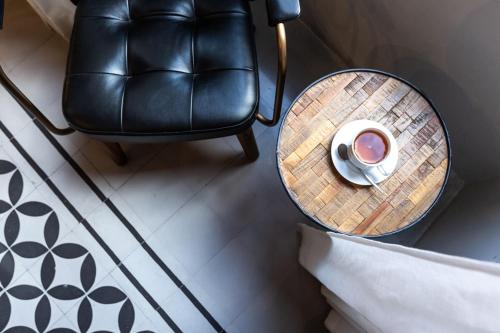 a table with a cup of coffee and a leather chair at Guest House de la Valette in Valletta