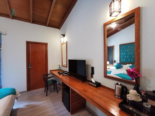 Schlafzimmer mit einem Schreibtisch, einem Spiegel und einem Bett in der Unterkunft Village Hideaways & Spas in Fulhadhoo