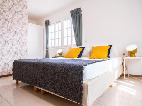 a bedroom with a large bed with yellow pillows at Casa Blu Guesthouse - Casa de Hospedes in Santa Maria