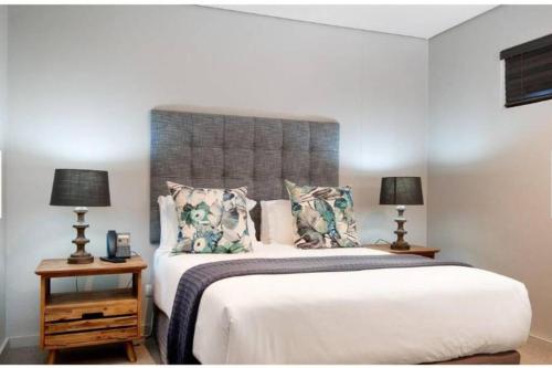 a bedroom with a large bed with two lamps at Zimbali Suite 112 in Ballito