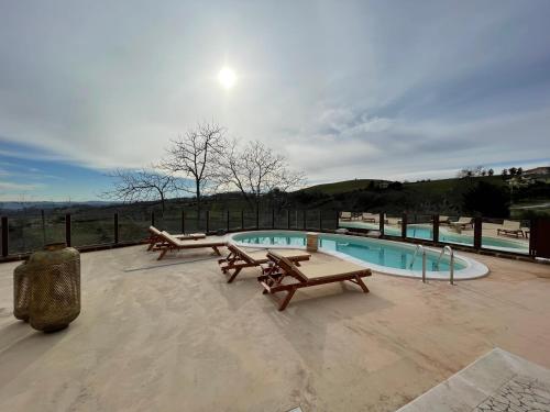 a swimming pool with picnic tables and benches on a patio at Dimora Rosso Piceno in Offida