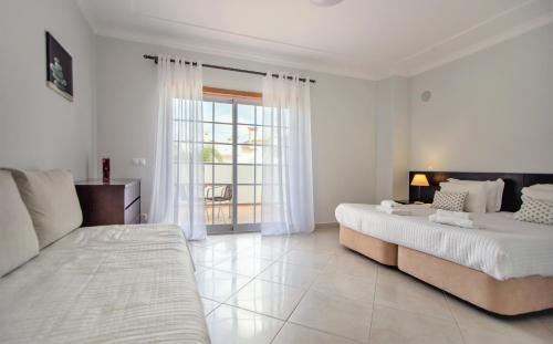 a white bedroom with two beds and a window at Villa Albufeira in Albufeira