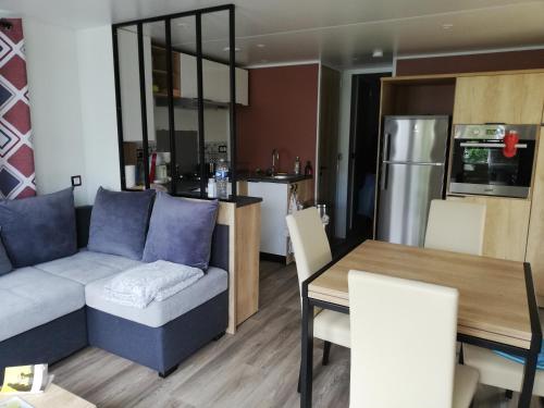 a living room and kitchen with a couch and a table at MOBILHOME GASTES LANDES in Gastes