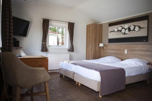 1 dormitorio con 2 camas, escritorio y TV en 2 2-persoons Hotel kamer, en Voorthuizen