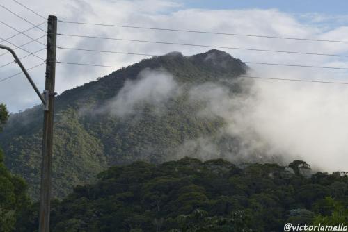 a mountain covered in mist and clouds next to a pole at A Casinha Lumiar in Lumiar