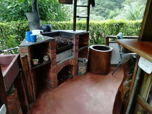 un horno de ladrillo al aire libre en un patio con un cubo de basura en Pochote Lodge en Guayabos