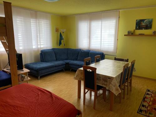 een woonkamer met een tafel en een blauwe bank bij Davos Lodge by Quokka 360 - practical apartment for skiers in Davos