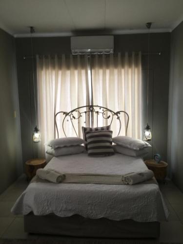 1 dormitorio con cama con almohadas y ventana en Spinoza Self Catering Accommodation, en Windhoek