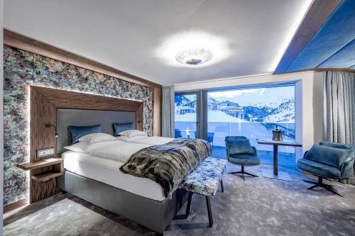 a bedroom with a large bed and a large window at Alpen-Wellness Resort Hochfirst in Obergurgl