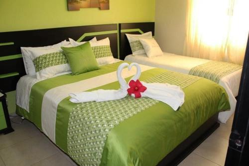 two beds with swans towels on them in a bedroom at Hotel Tababela Land in Tababela