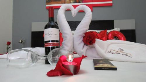 a table with a bottle of wine and a candle and roses at Hotel Tababela Land in Tababela
