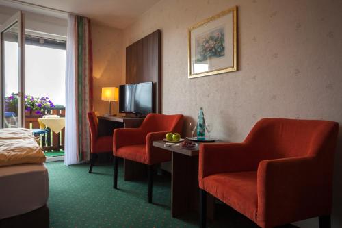 a hotel room with red chairs and a television at Hotel Berghof in Willingen