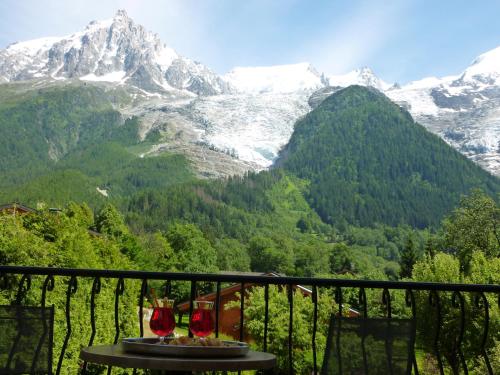 a table with two wine glasses on a balcony with mountains at Aiguille du Midi - Hôtel & Restaurant in Chamonix-Mont-Blanc
