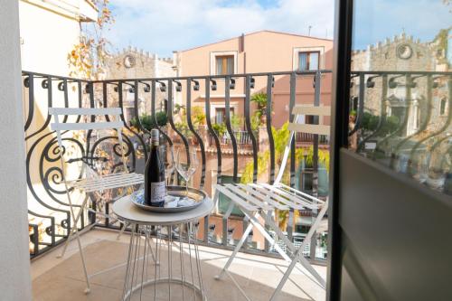 a balcony with two chairs and a table with a bottle of wine at Longo Suites in Taormina