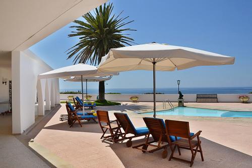 a group of chairs and umbrellas next to a swimming pool at Casa Três Palmeiras in Portimão