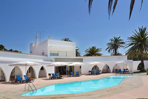 a resort with a swimming pool and chairs and umbrellas at Casa Três Palmeiras in Portimão