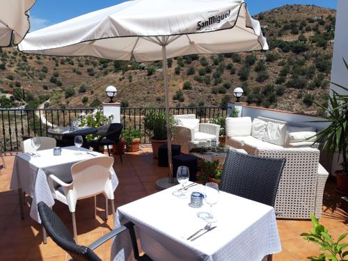 a patio with tables and chairs and an umbrella at Hotel La Casa in Torrox