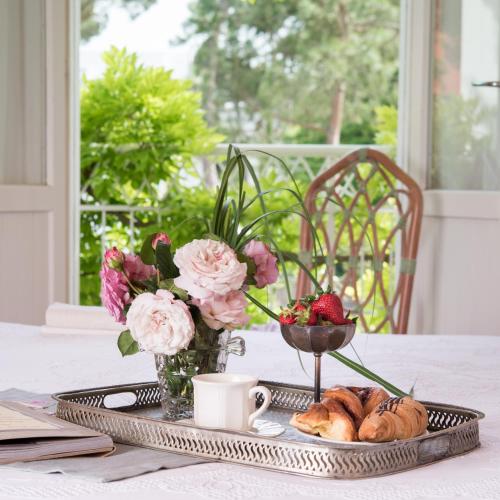 a tray with pastries and a cup of coffee and flowers at Villa Arizona in Milano Marittima