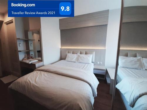 a hotel room with a bed and a mirror at Apartemen Grand Kamala Lagoon Studio By Bonzela Property in Bekasi