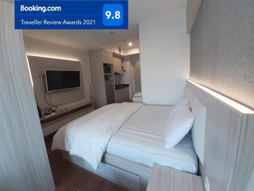 a bedroom with a white bed and a tv at Apartemen Grand Kamala Lagoon Studio By Bonzela Property in Bekasi