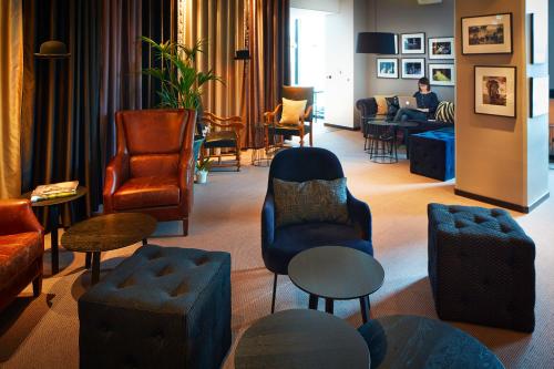 a lobby with chairs and tables and a person sitting at a desk at Best Western Plus Hotel Plaza in Västerås