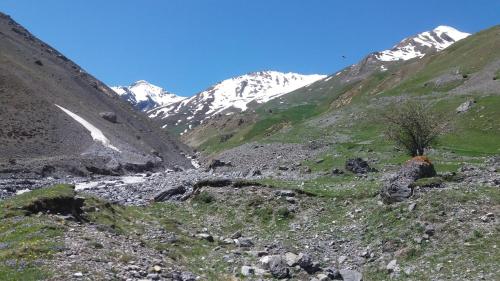 a mountain valley with a river and snow covered mountains at Aiguille Noire in Valloire