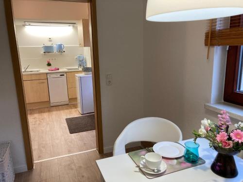 a dining table with a white chair and a kitchen at Appartement 2 Garten in Bergen auf Rügen