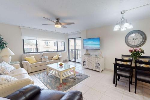 a living room with a couch and a table and a clock at Siesta Sands Beach Resort 4th Floor with Elevator in Sarasota