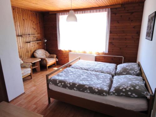 a bedroom with a bed and a window and a chair at Villa- Caba in Křemže