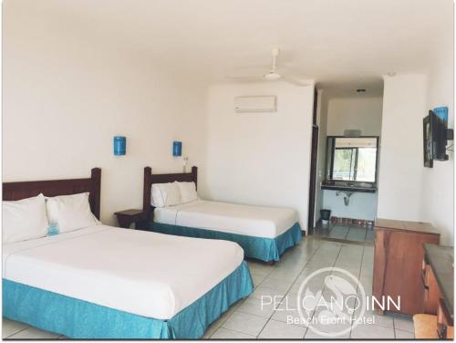 a hotel room with two beds and a television at Pelicano Inn Playa del Carmen - Beachfront Hotel in Playa del Carmen
