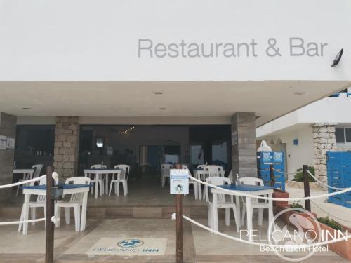 a restaurant and bar with white tables and chairs at Pelicano Inn Playa del Carmen - Beachfront Hotel in Playa del Carmen