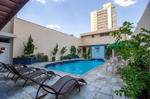 a swimming pool with chairs and a building at Hotel Nacional Inn Araçatuba in Araçatuba