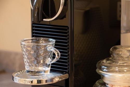 a glass mug on a stand next to a toaster oven at Longo Suites in Taormina