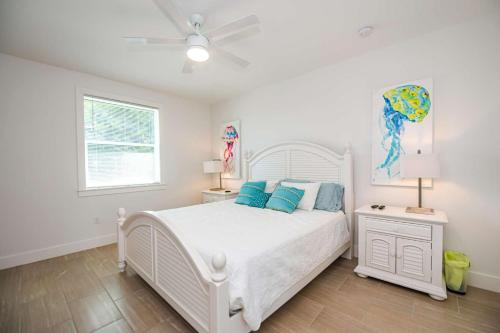 a bedroom with a white bed with blue pillows at Lido Dream Getaway Duplex N in Sarasota