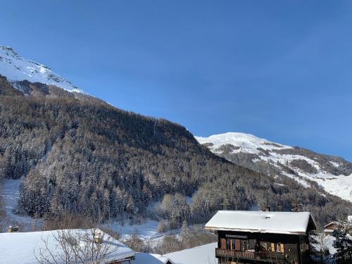 a house in the snow with a mountain at Hôtel Restaurant Eden in Evolène
