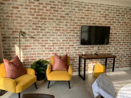 een slaapkamer met 2 stoelen en een tv aan een bakstenen muur bij Pont de Val - La Rivière Apartments in Parys