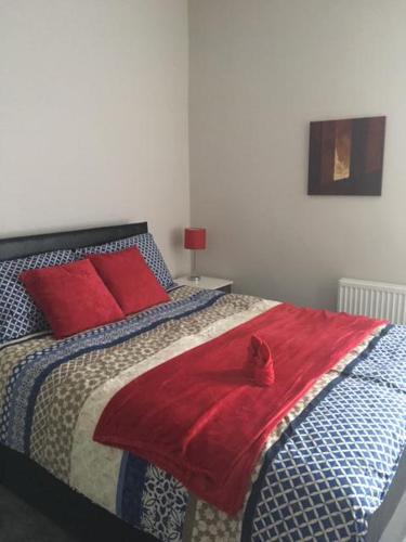 Townhouse @ Corporation Street Stoke في ستوك أون ترينت: غرفة نوم مع سرير مع بطانية حمراء عليه