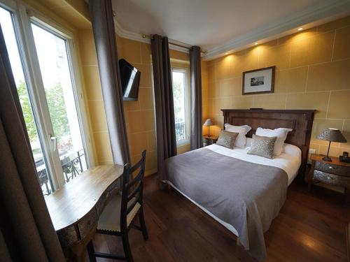 a bedroom with a bed and a desk and windows at Hôtel du Château in Vincennes