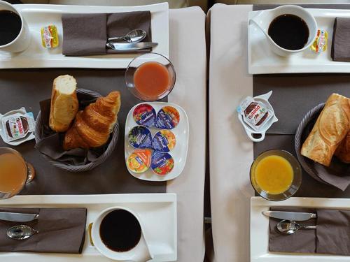 a table with plates of food and cups of coffee at Hôtel du Château in Vincennes