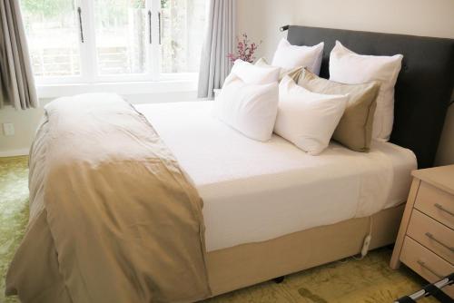 a bedroom with a bed with white sheets and pillows at Apartment on St Georges in Havelock North