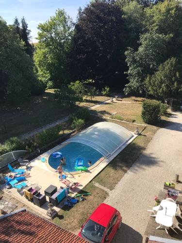 een uitzicht over een zwembad met een rode auto bij les chambres du parc in Dammarie-sur-Saulx