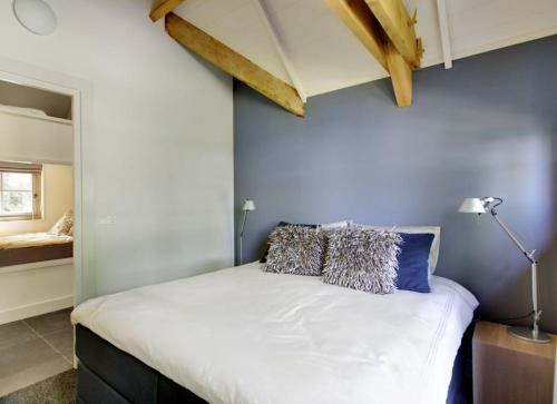 a bedroom with a white bed with a blue wall at Vlindervallei 8p in Ermelo
