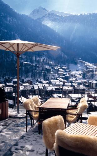 a table and chairs with an umbrella on a balcony at The Omnia in Zermatt